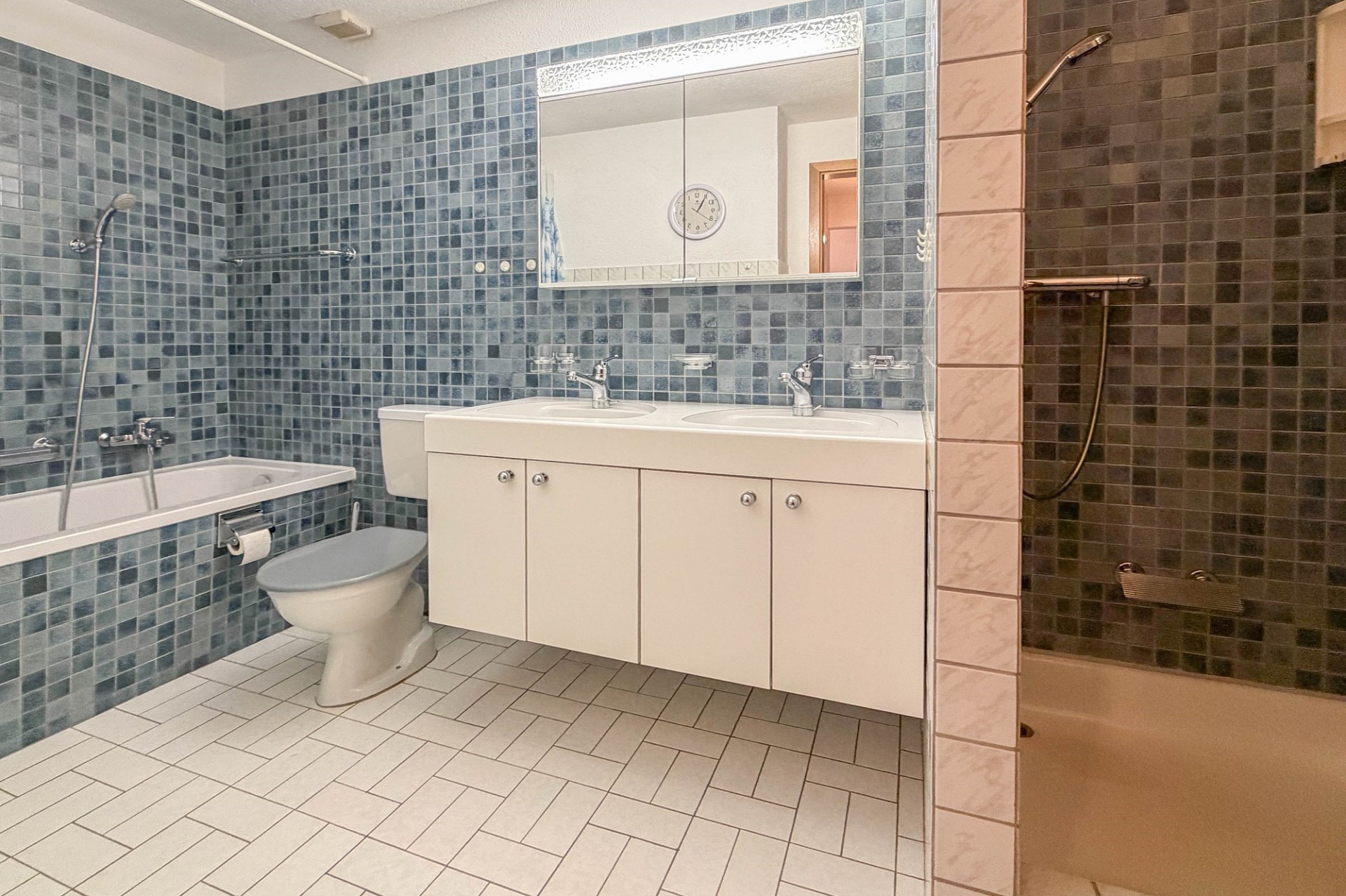 Badezimmer mit blauem Mosaik, Doppelwaschtisch und Wanne