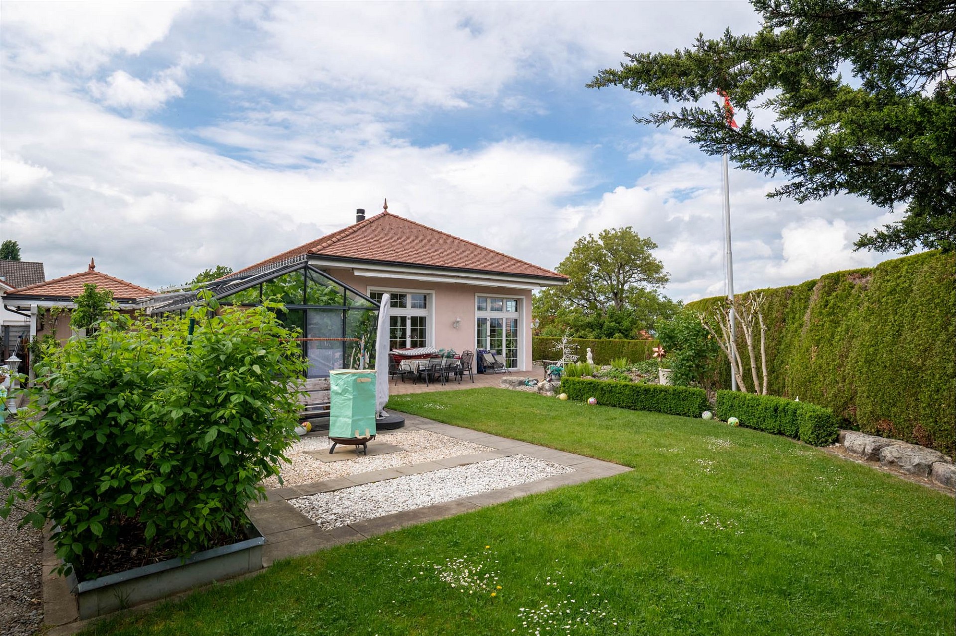 Gepflegter Garten mit eingeschossigem Haus und Wintergarten