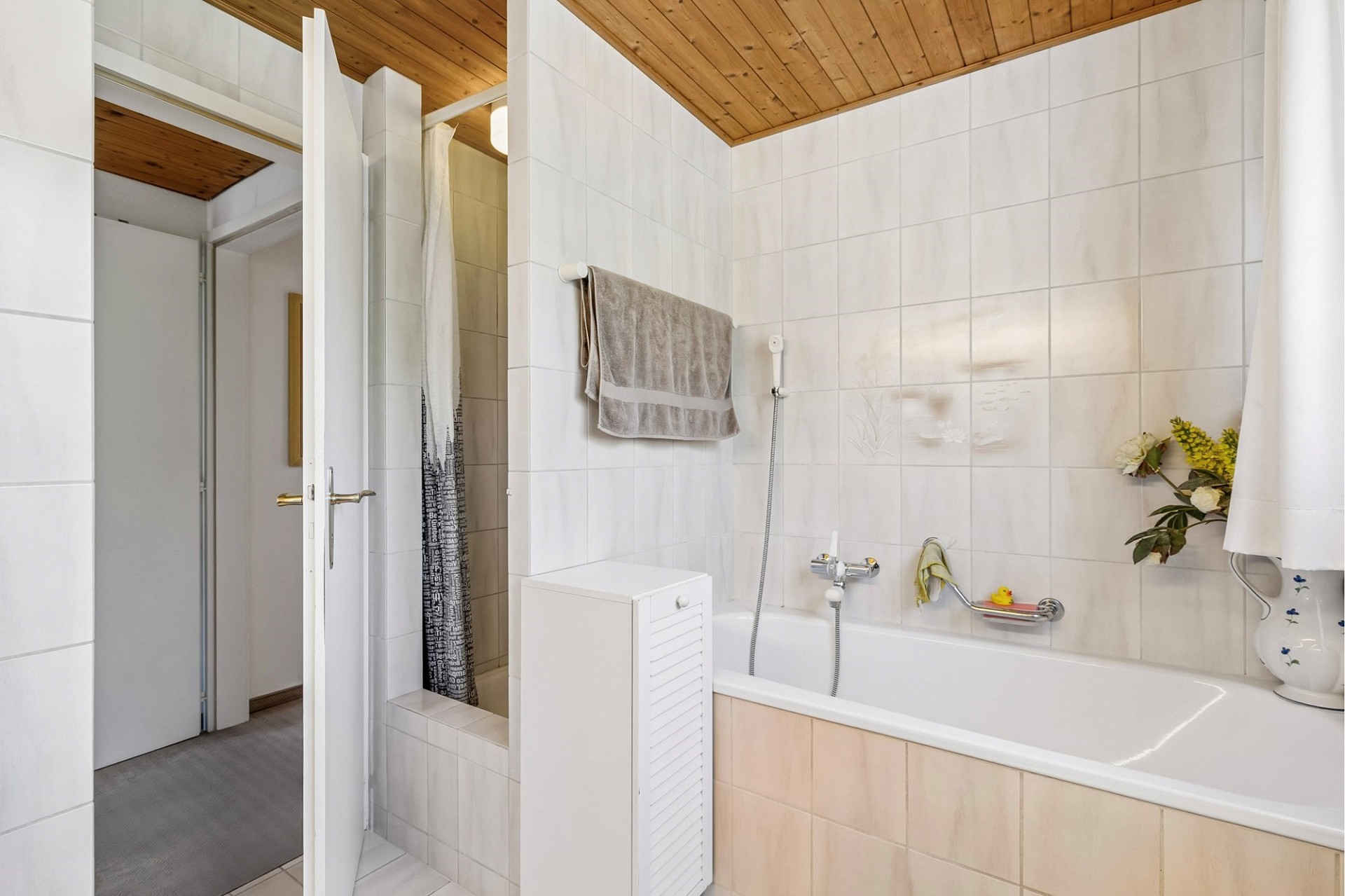 Helles Badezimmer mit Badewanne und Holzdecke