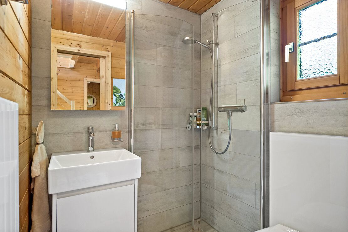 Modernes Badezimmer mit Holzverkleidung und Glasdusche