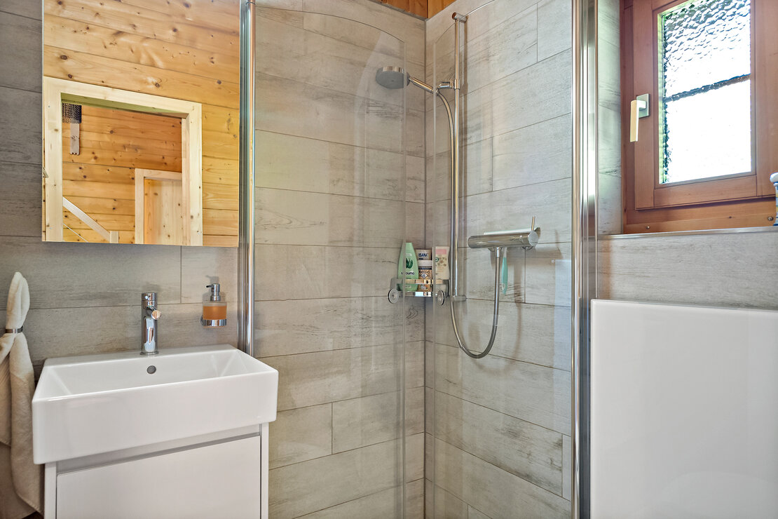Modernes Badezimmer mit Glasdusche und Holzdetails