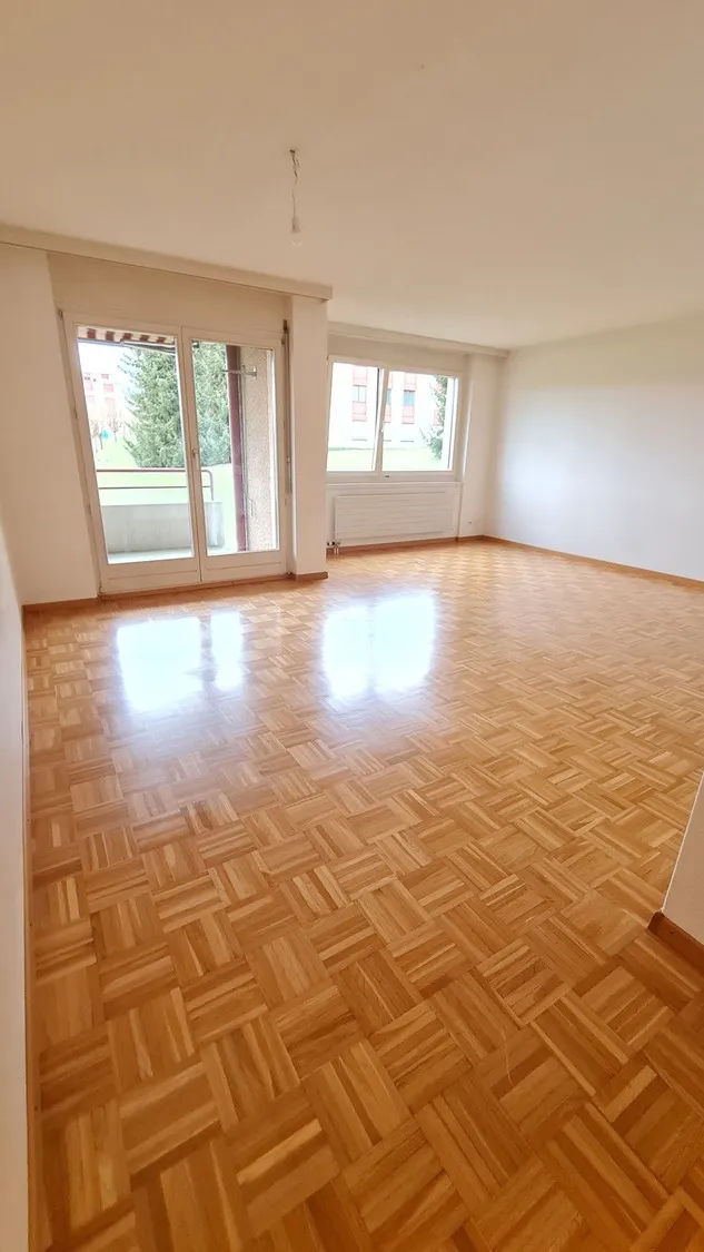 Heller leerer Wohnraum mit Parkett und Balkon