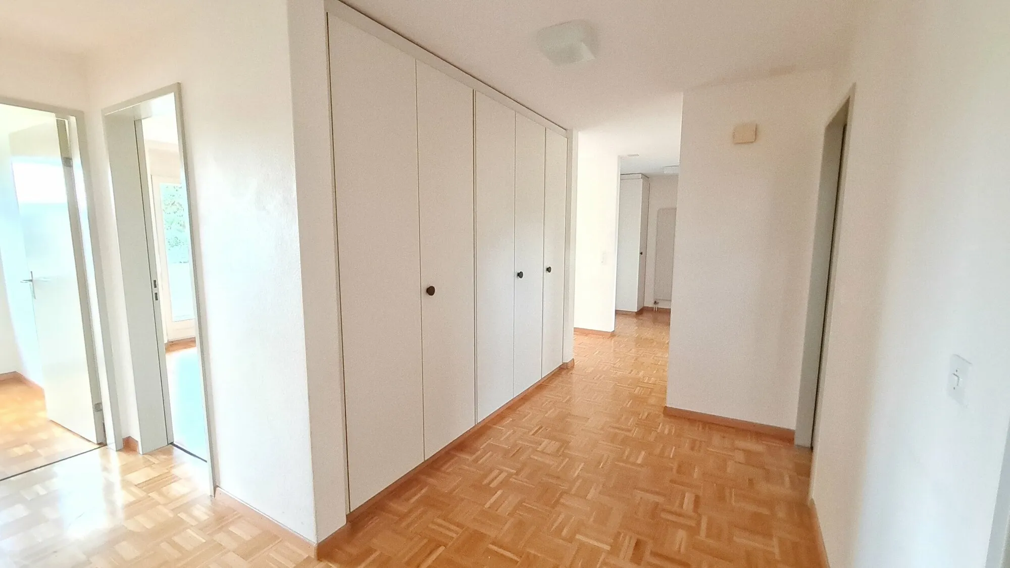 Heller Flur mit Einbauschränken und Parkettboden