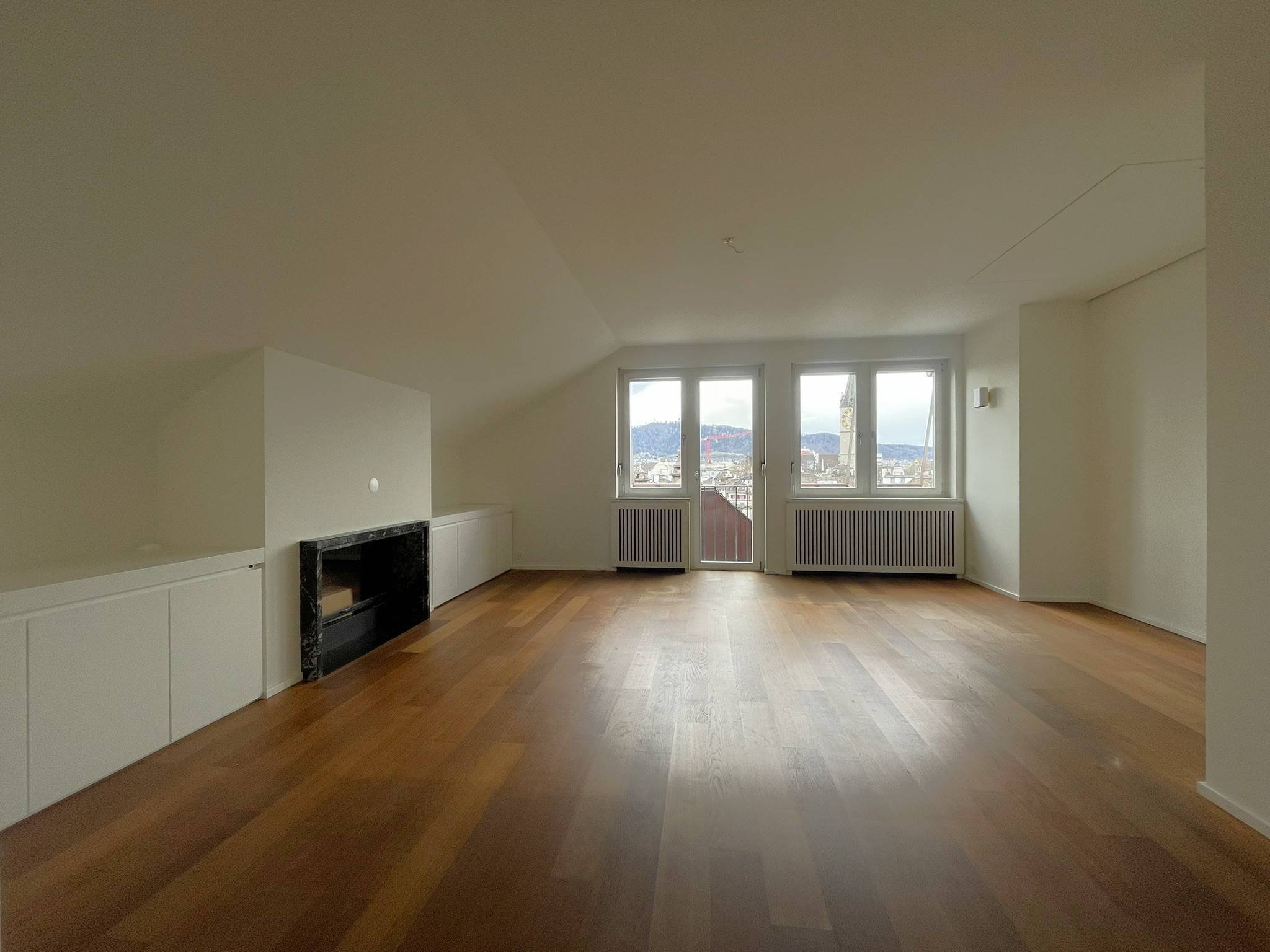 Dachgeschoss-Wohnraum mit Kamin und Stadtblick
