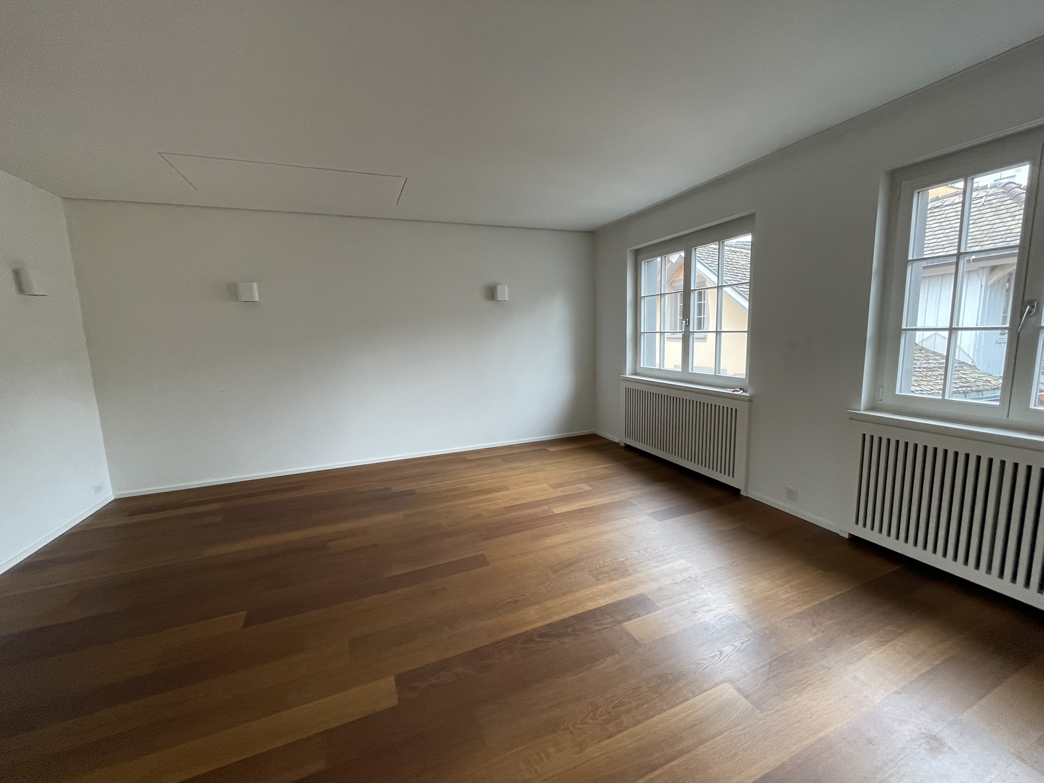 Leerer heller Raum mit Parkett und Fenstern
