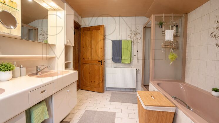 Helles Badezimmer mit Badewanne und Holztür