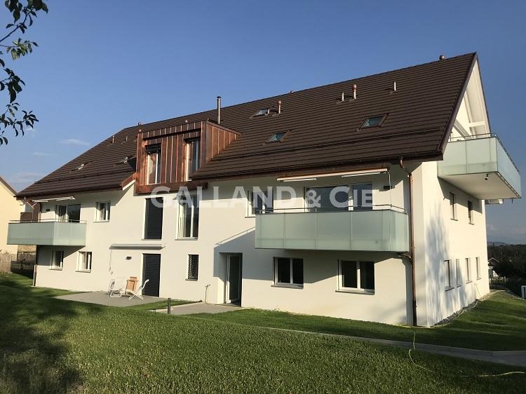 Mehrfamilienhaus mit dunklem Satteldach und Glasbalkonen