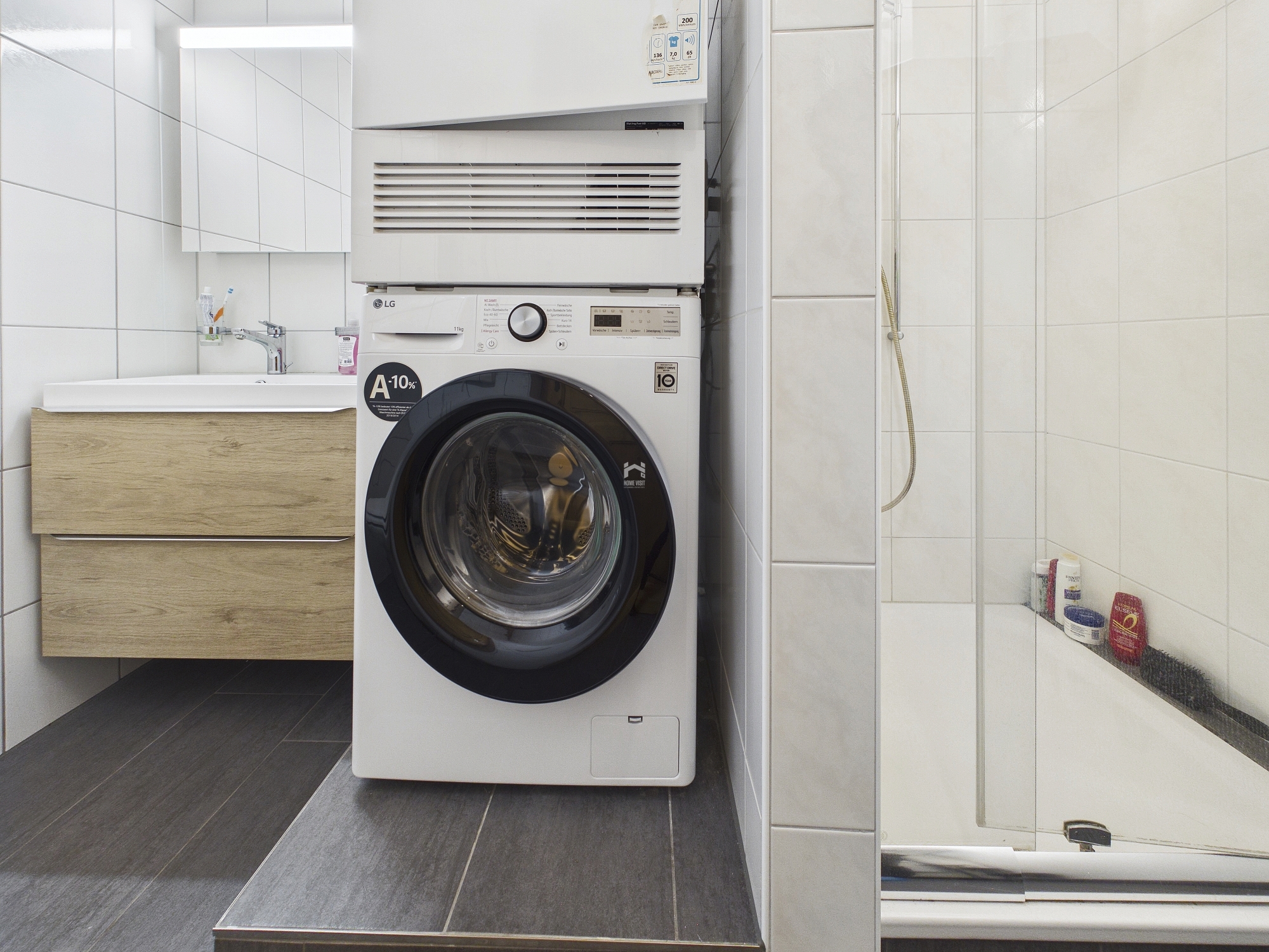 Badezimmer mit Waschtisch, Waschmaschine und Dusche