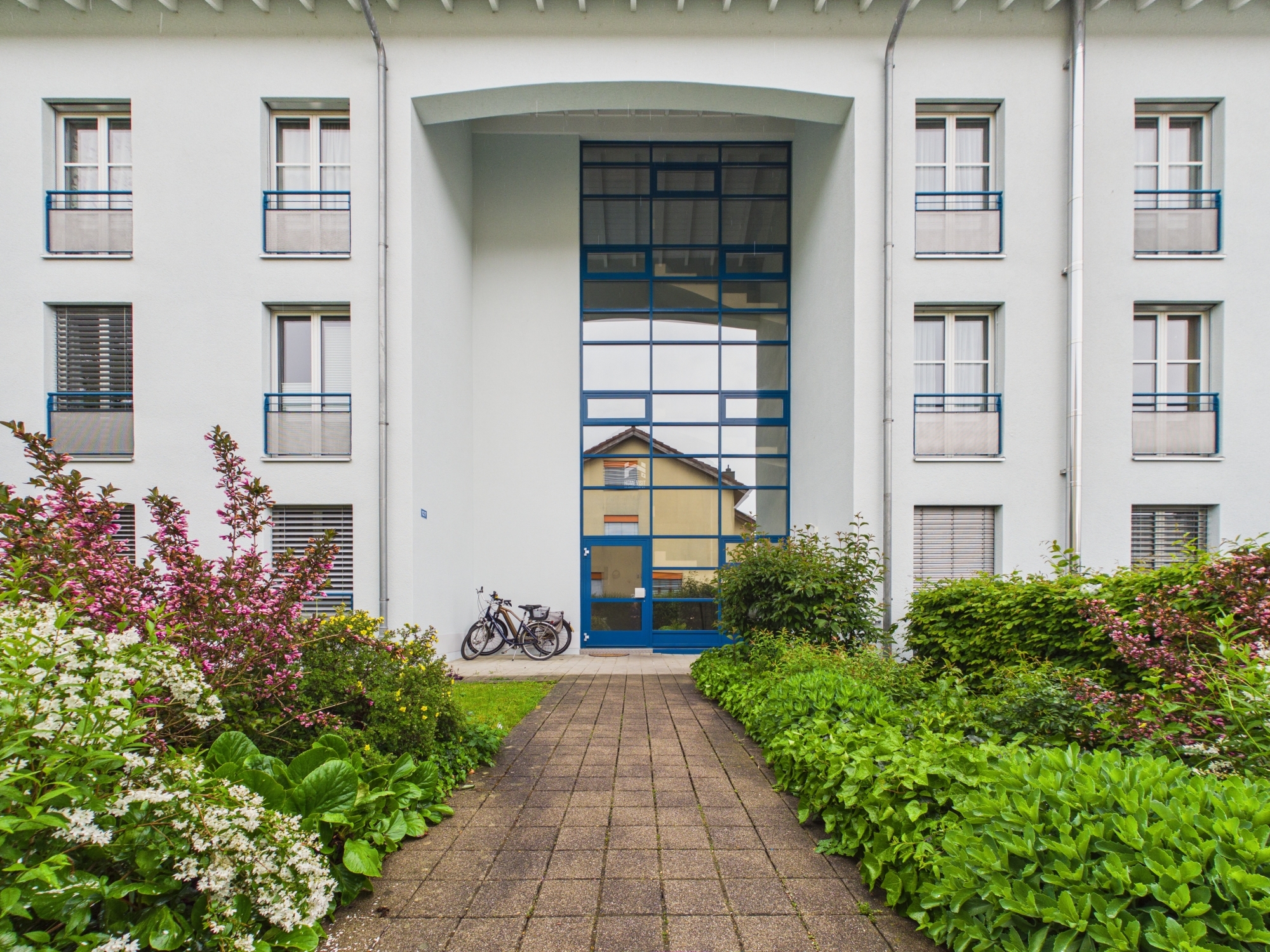 Modernes Wohngebäude mit zentralem Eingang und Gartenweg