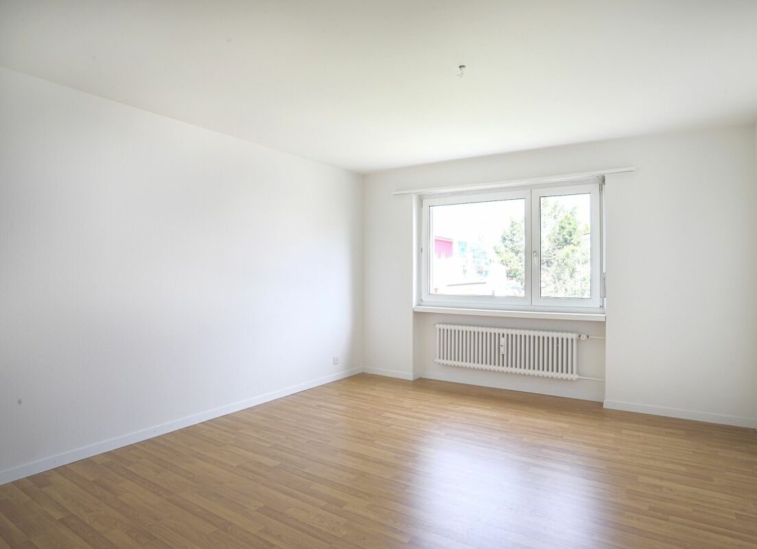 Leerer heller Wohnraum mit Fenster und Heizkörper