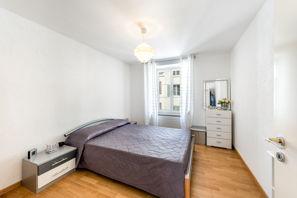 Schlichtes Schlafzimmer mit Doppelbett und Fenster