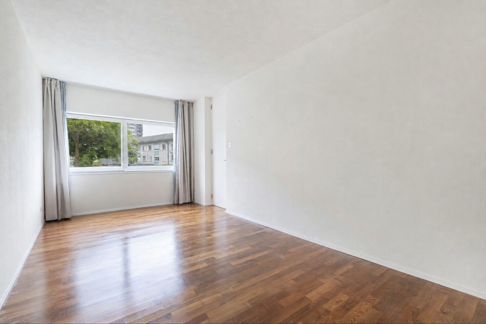 Heller, leerer Wohnraum mit Fensterfront