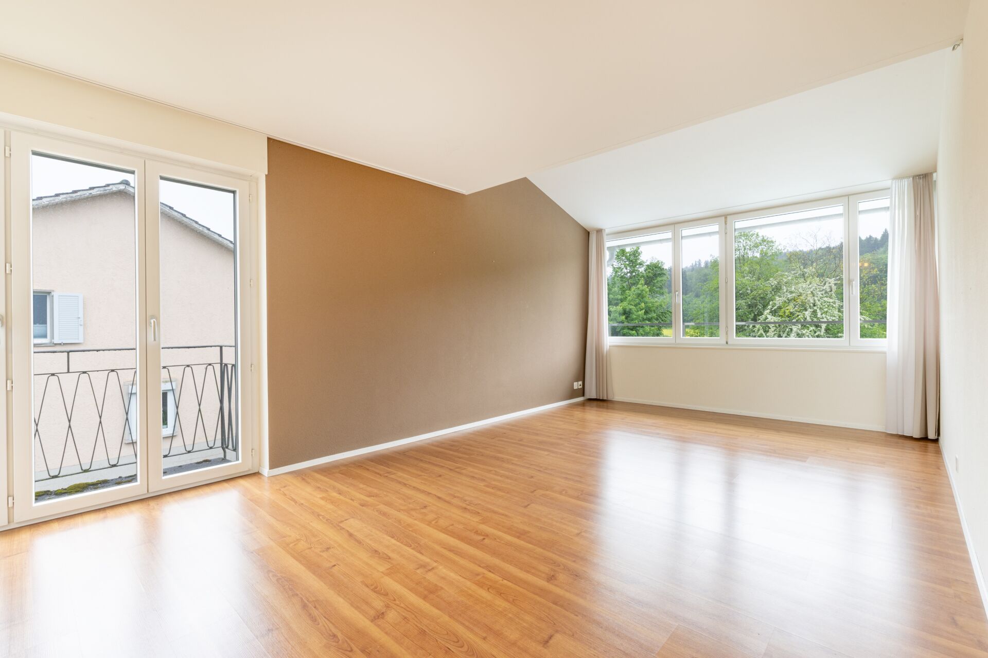 Heller leerer Wohnraum mit Balkon und Waldblick