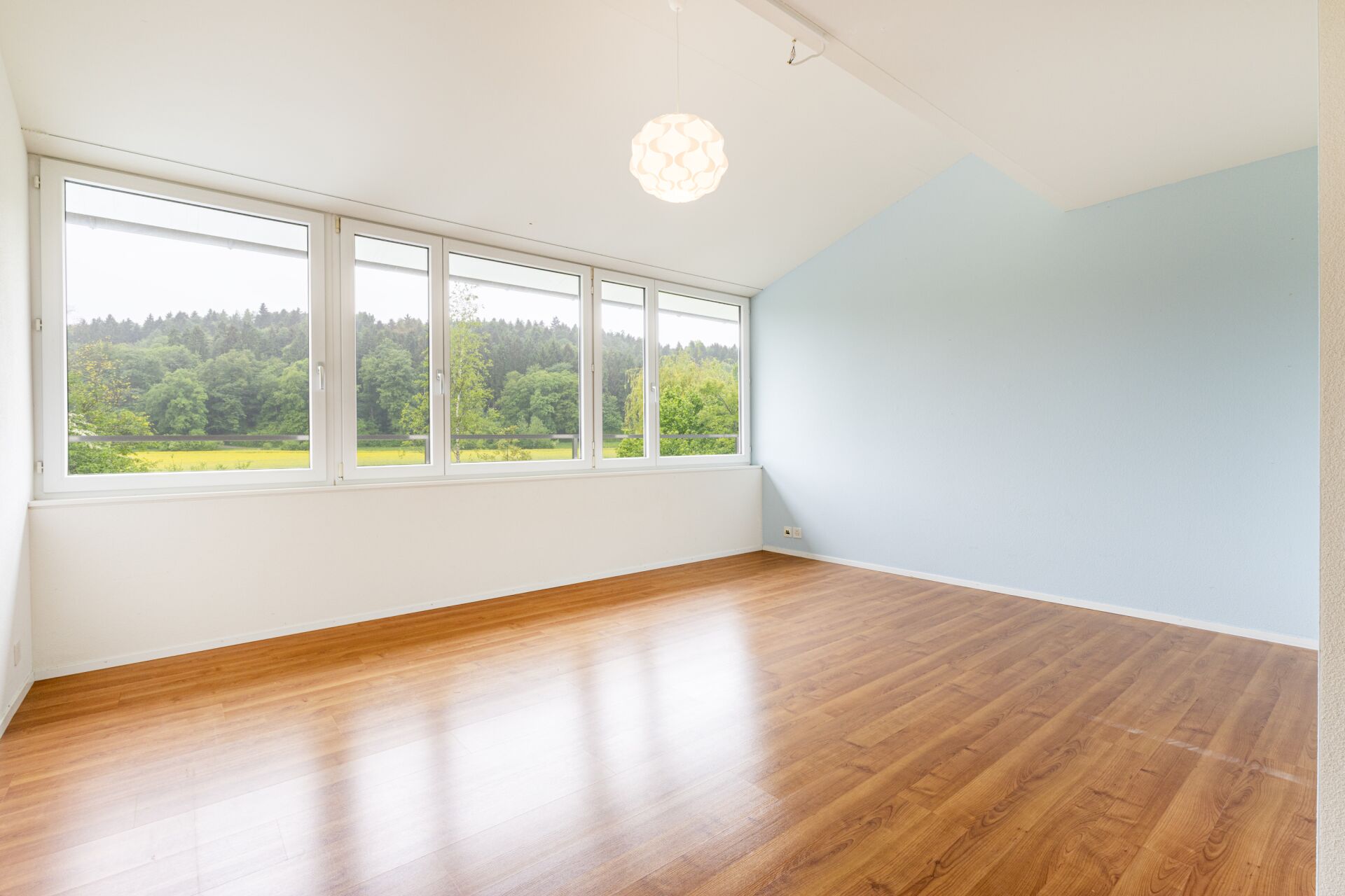 Heller leerer Raum mit Holzoptikboden und Panoramafenstern