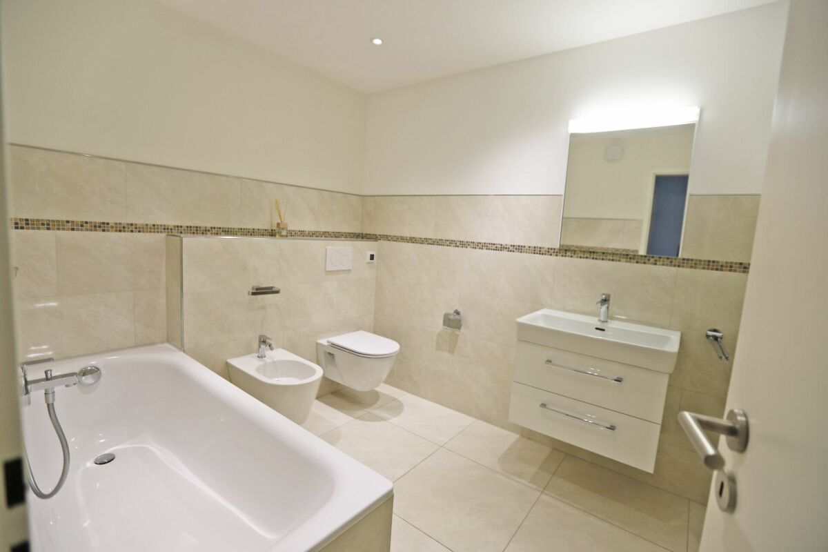 Helles, modernes Badezimmer mit Badewanne, Waschtisch und WC