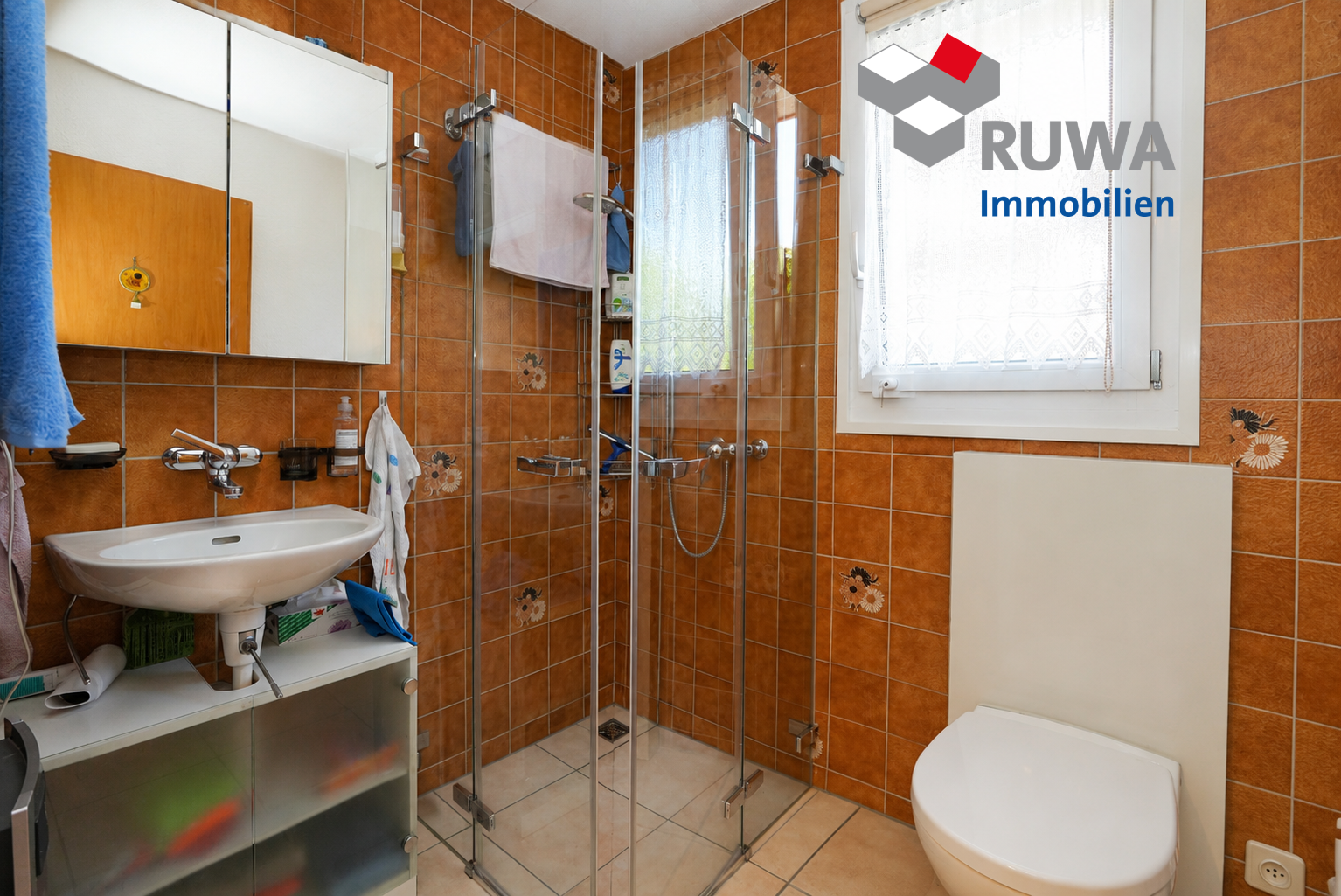 Badezimmer mit orangefarbenen Fliesen und Glasdusche