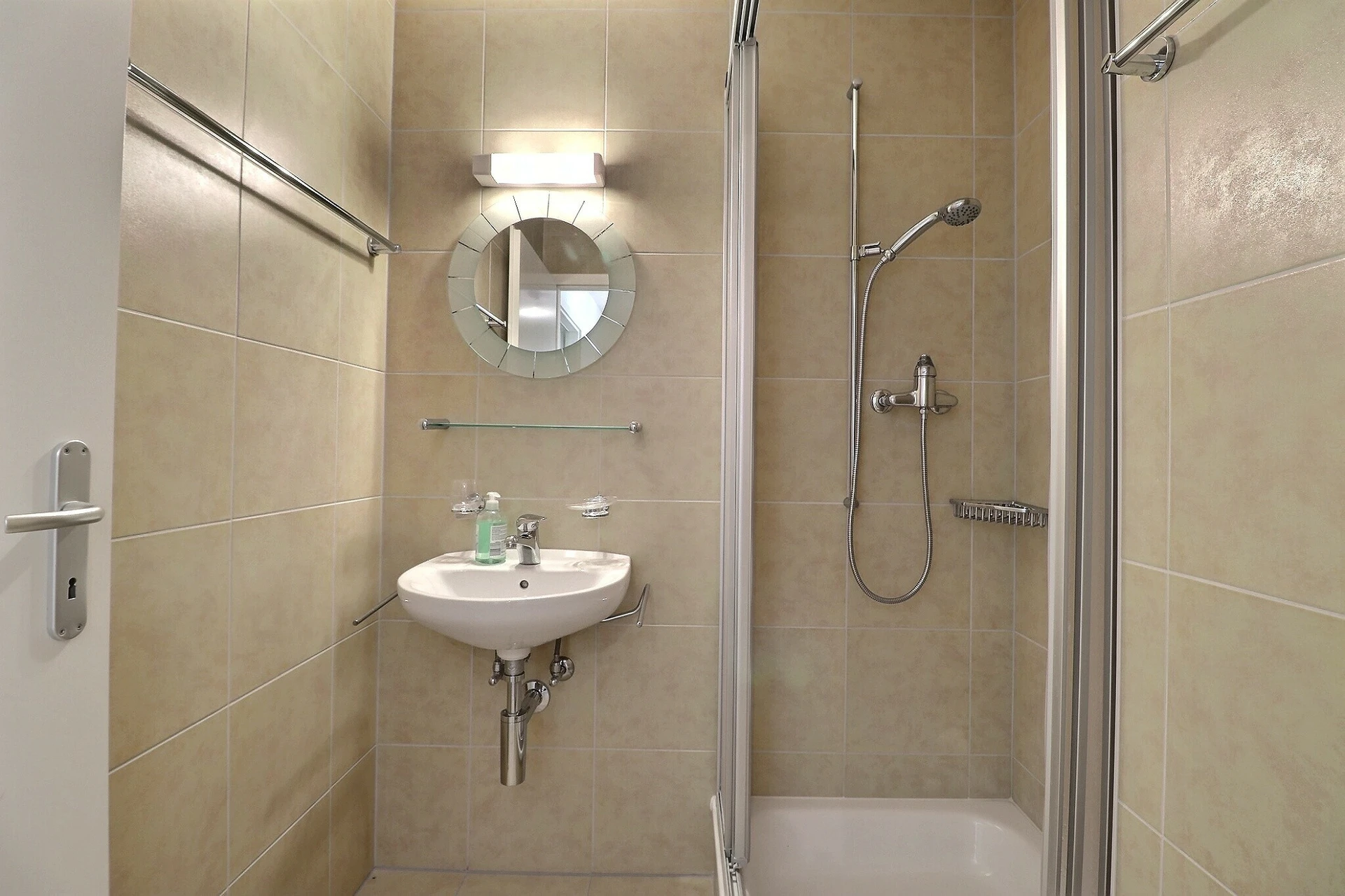Kleines beige gefliestes Badezimmer mit Dusche und Waschbecken