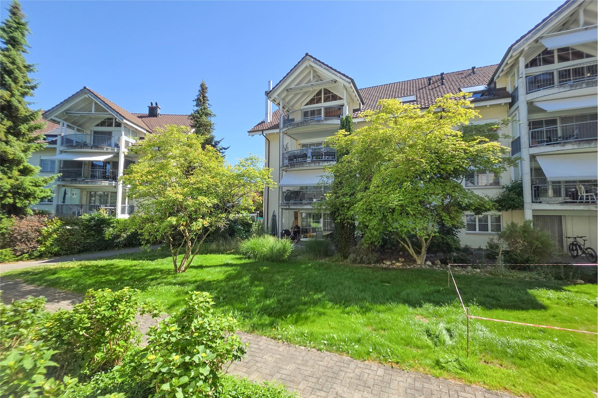 Mehrfamilienhaus mit Giebelbalkonen und Grünanlage