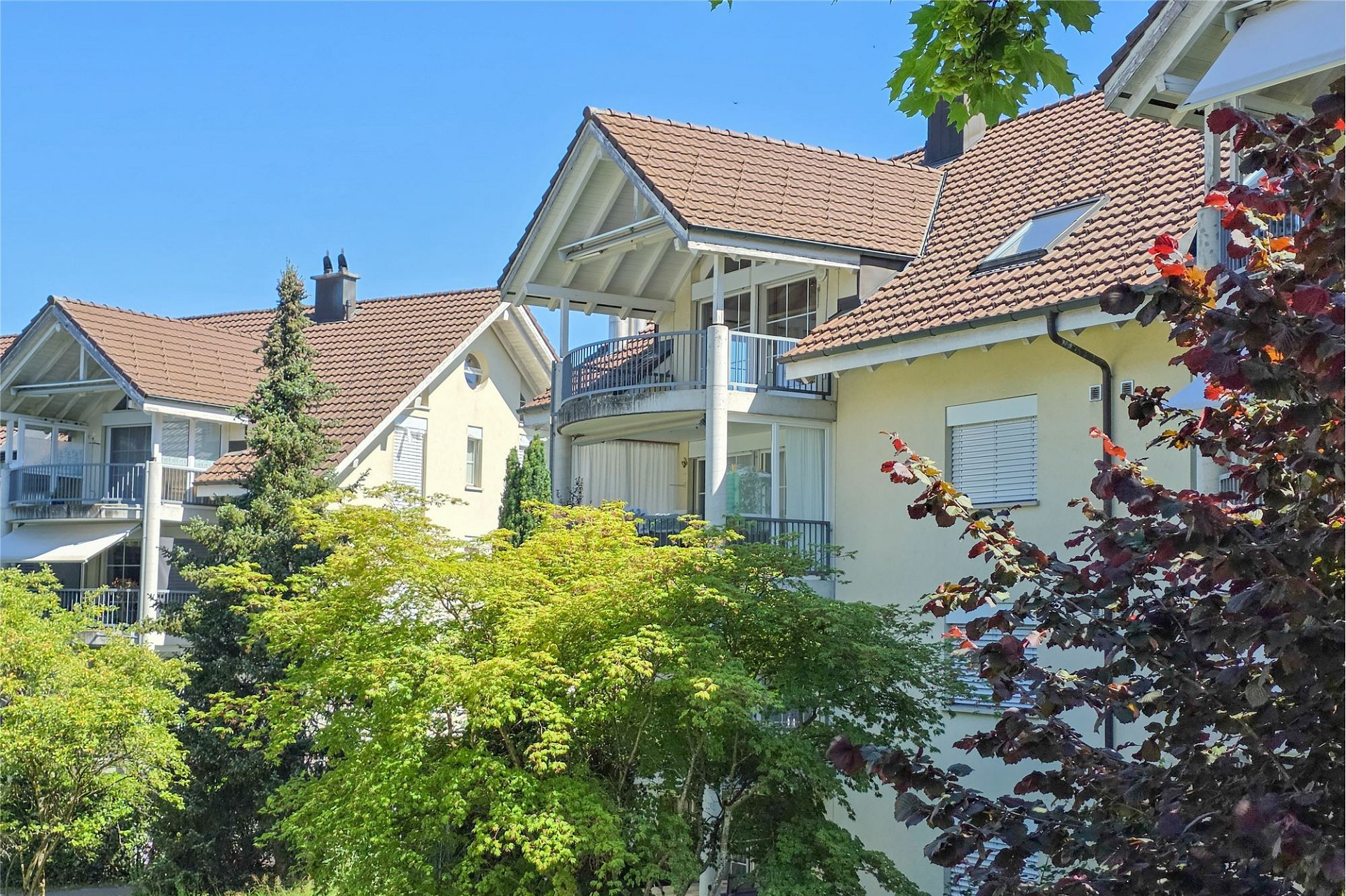 Mehrfamilienhaus mit roten Ziegeldächern und Balkonen
