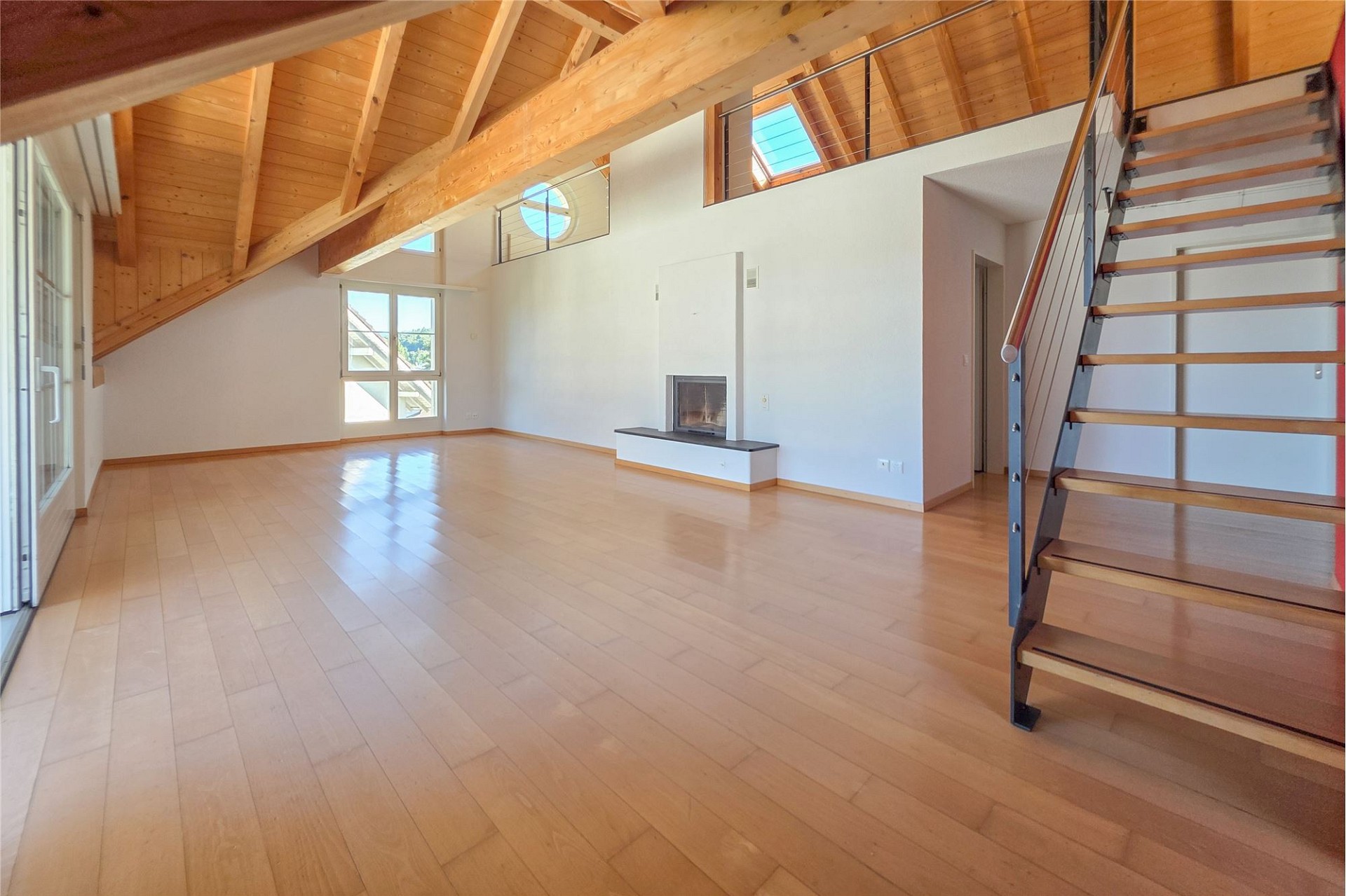 Heller offener Wohnraum mit Galerie und Holzbalkendecke