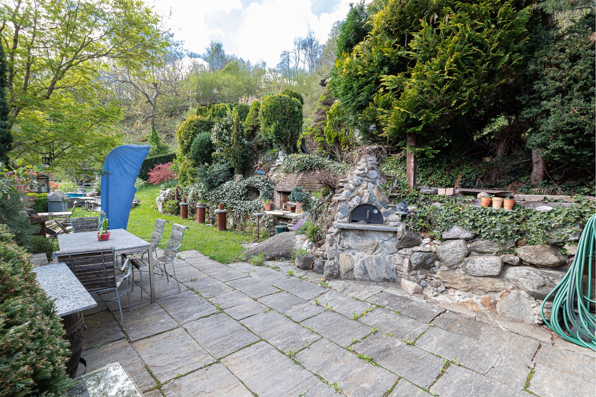 Gepflegte Gartenterrasse mit Steinbelag und Feuerstelle