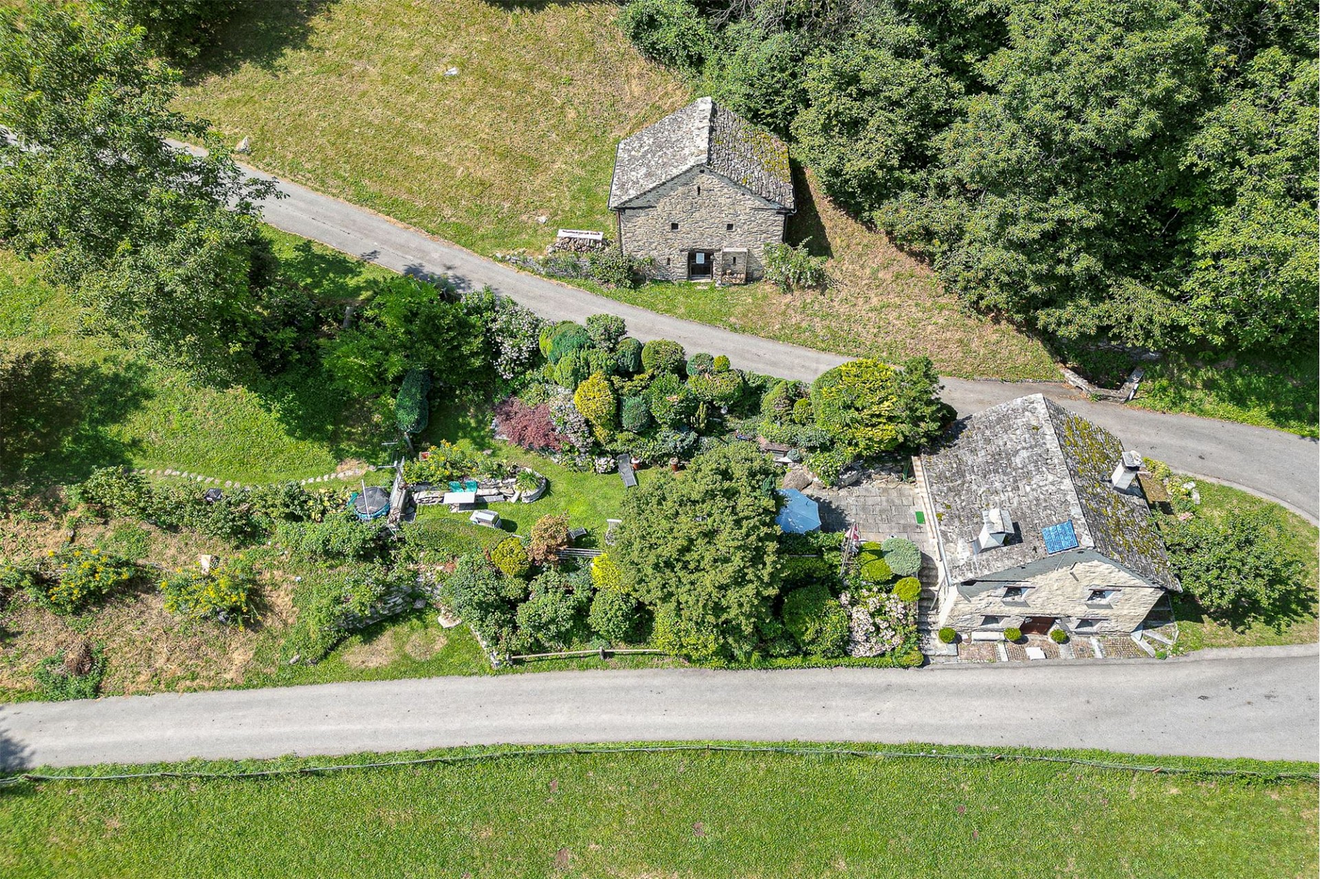 Luftaufnahme eines ländlichen Anwesens mit zwei Steinhäusern und Garten