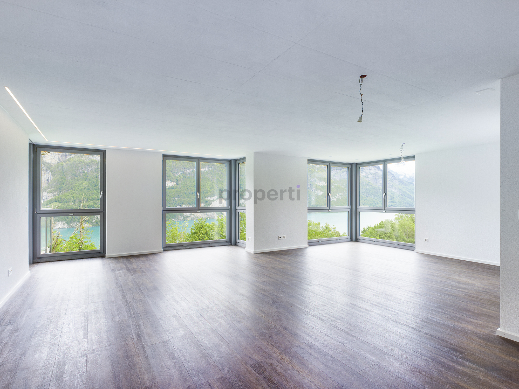 Heller leerer Wohnraum mit Panoramafenstern und Seeblick