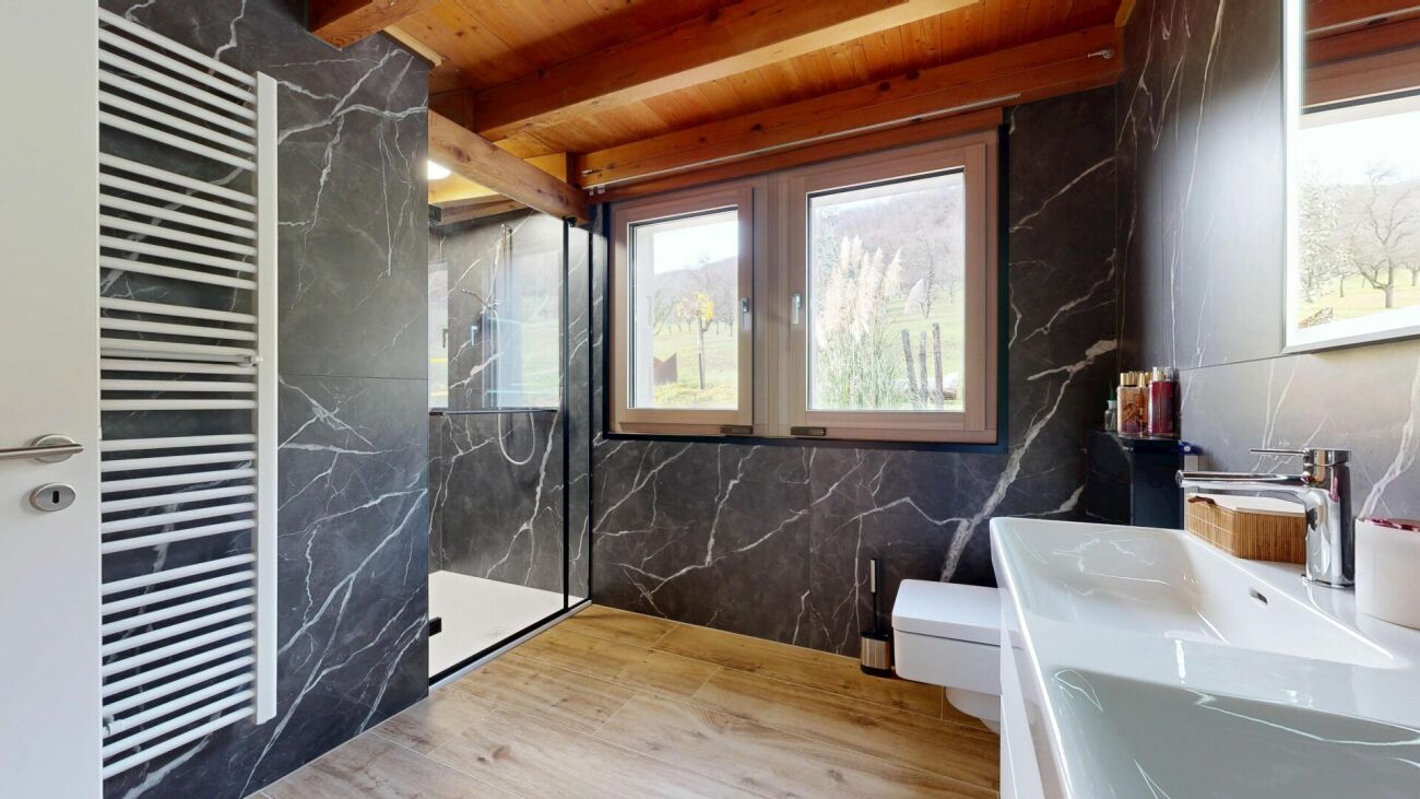 Modernes Badezimmer mit dunkler Steinoptik und Holzdecke