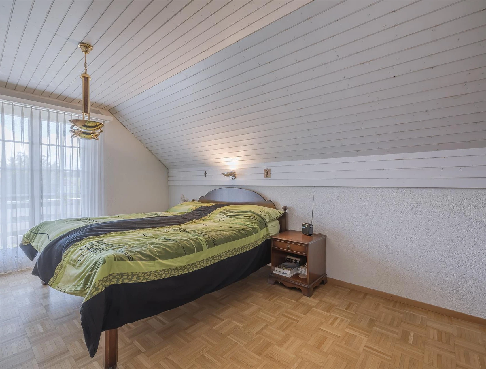 Dachgeschoss-Schlafzimmer mit Bett und Fensterfront