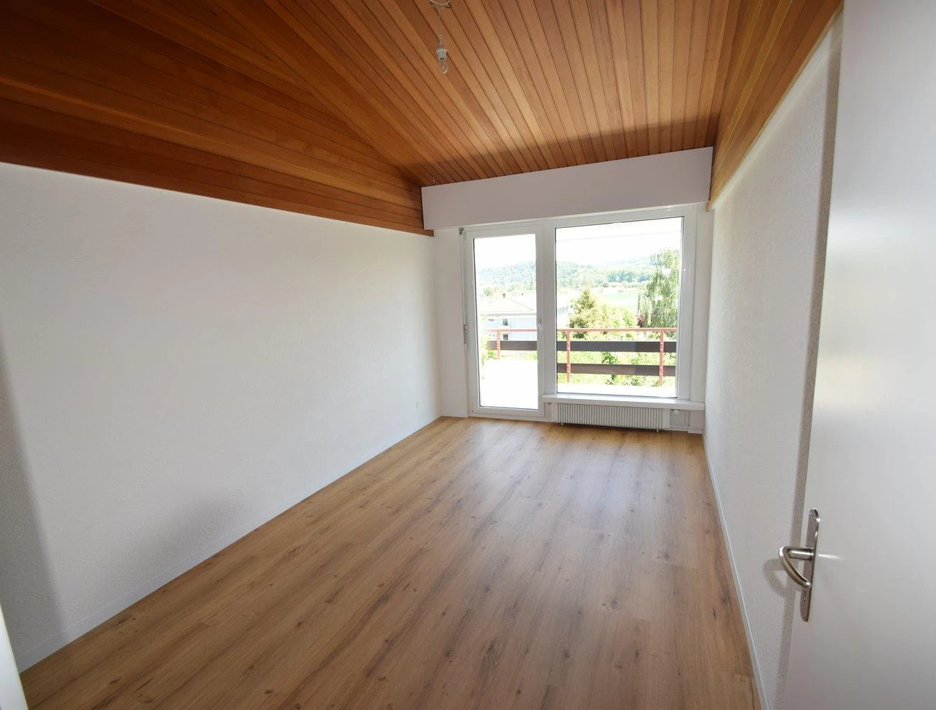 Leeres Zimmer mit Holzdecke und Balkonblick