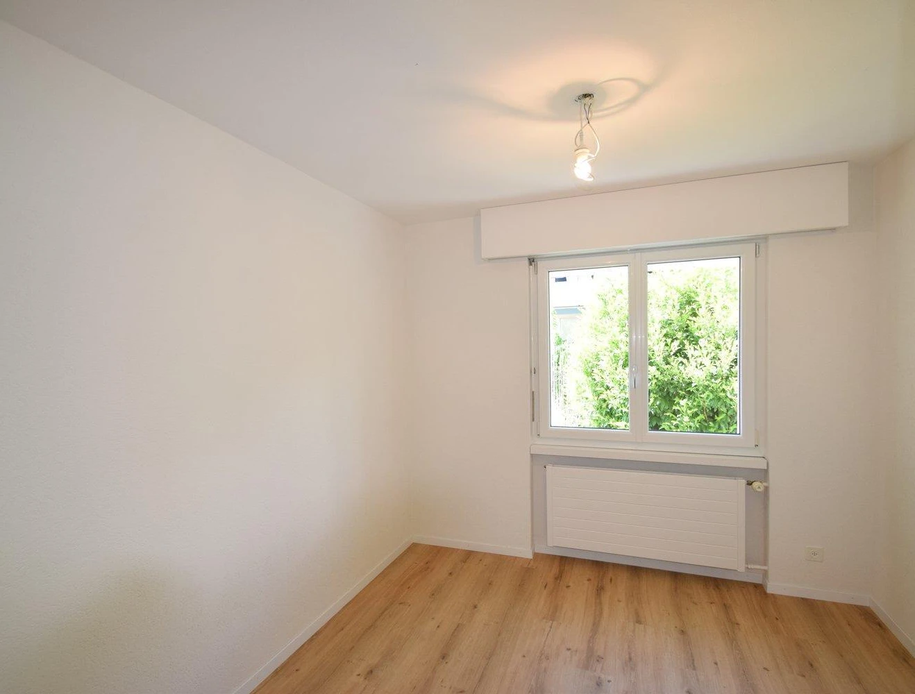 Leerer heller Raum mit Fenster und Heizkörper