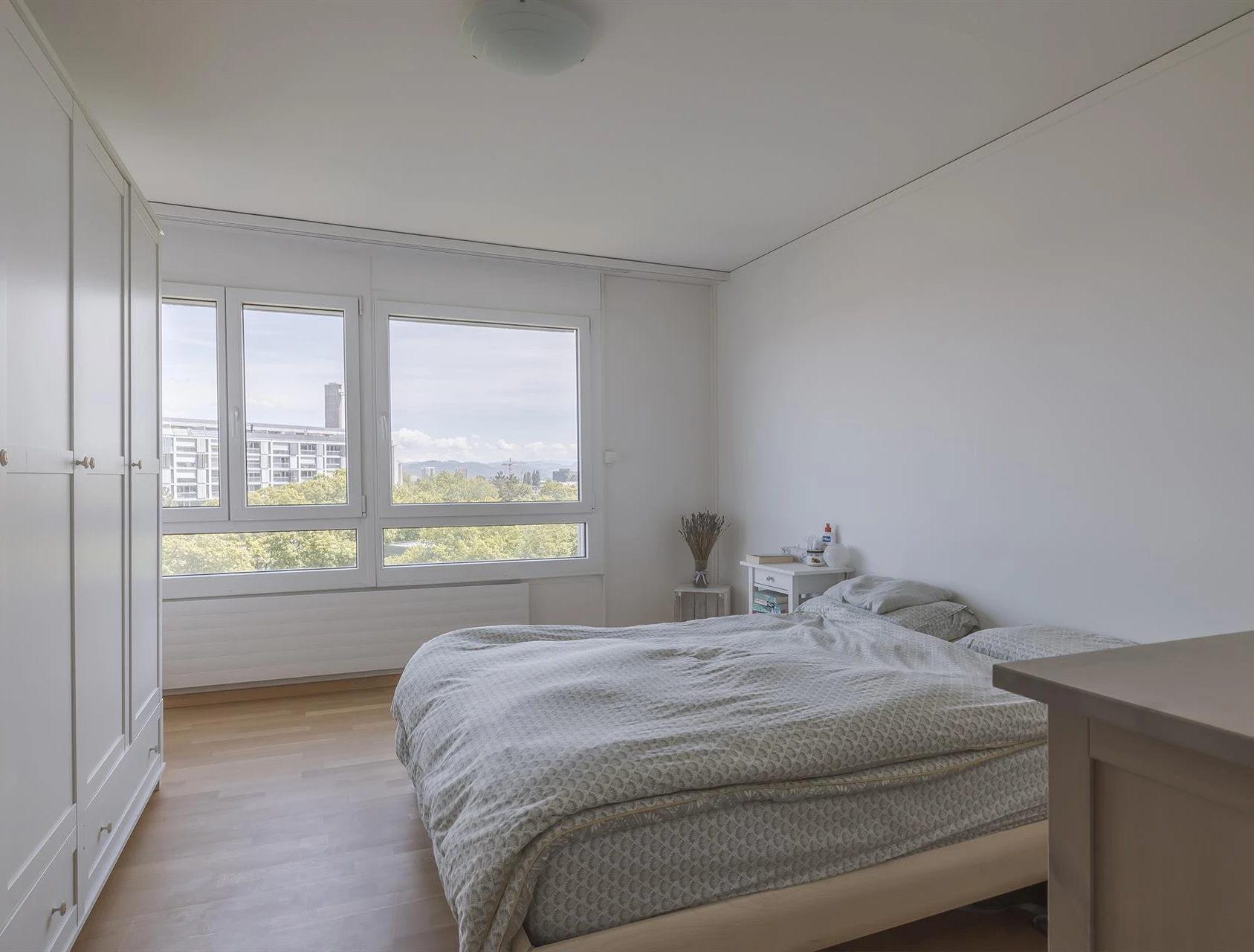 Helles Schlafzimmer mit großem Fenster und weißer Einrichtung