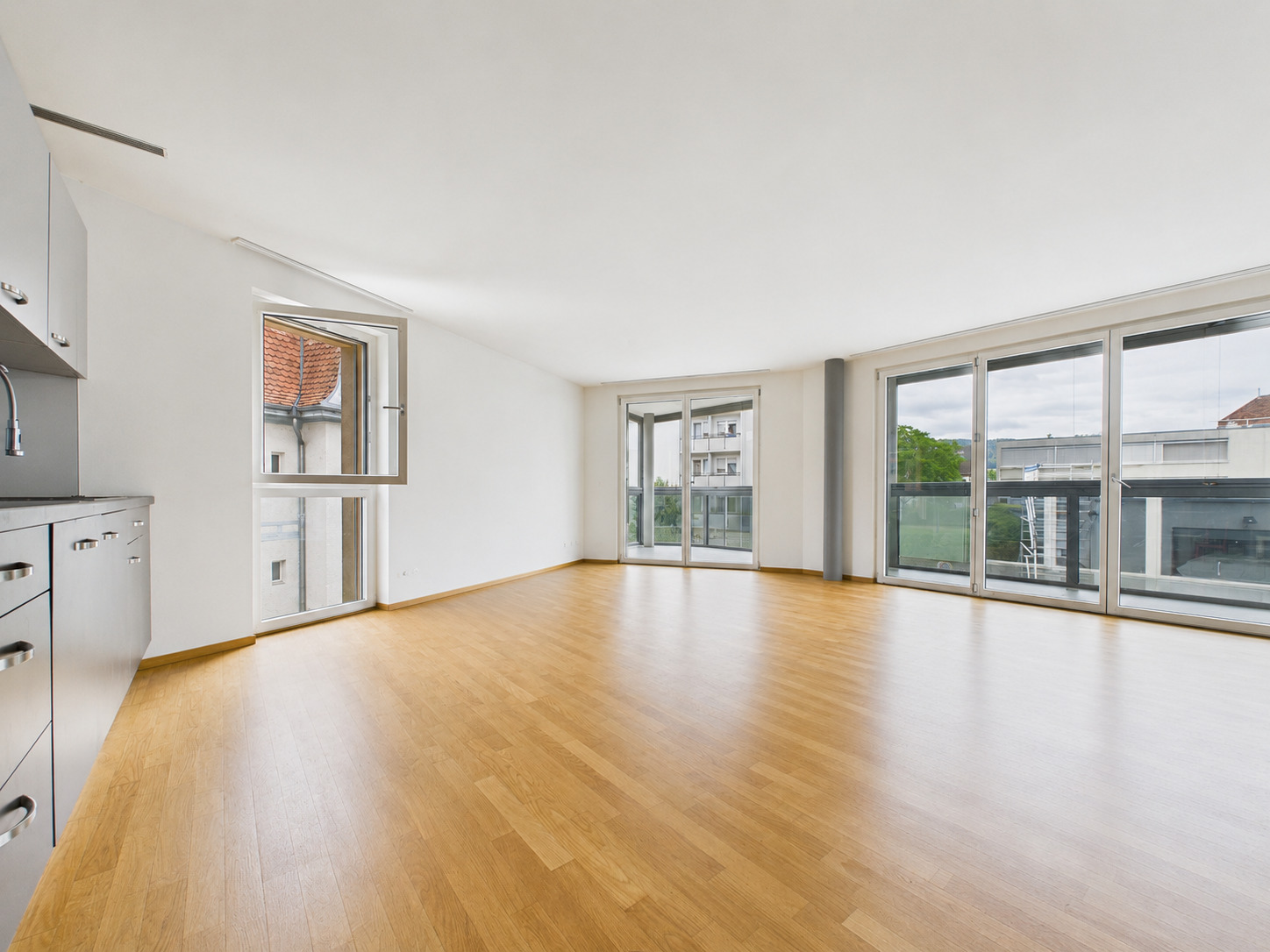 Großer leerer Wohnraum mit Balkonfenstern