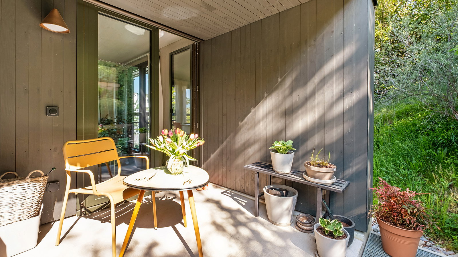Überdachte Terrasse mit Sitzgruppe und Pflanzen