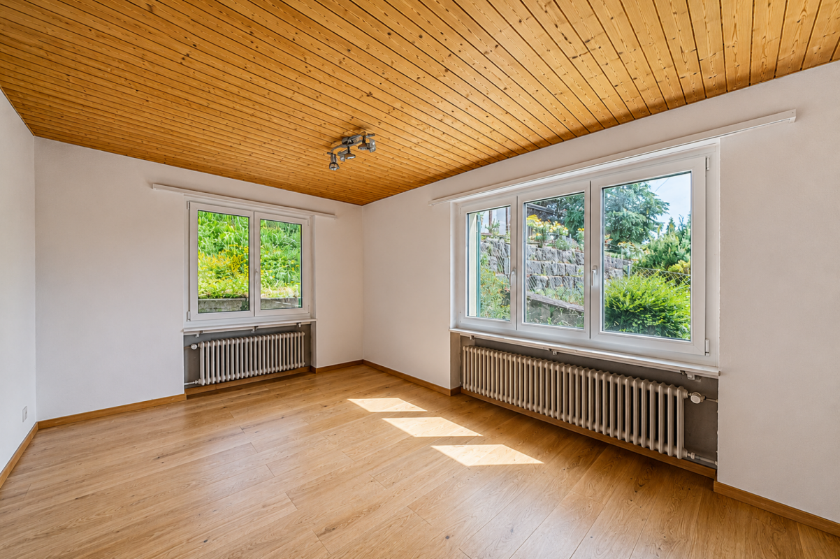Heller leerer Raum mit Holzdecke und großen Fenstern