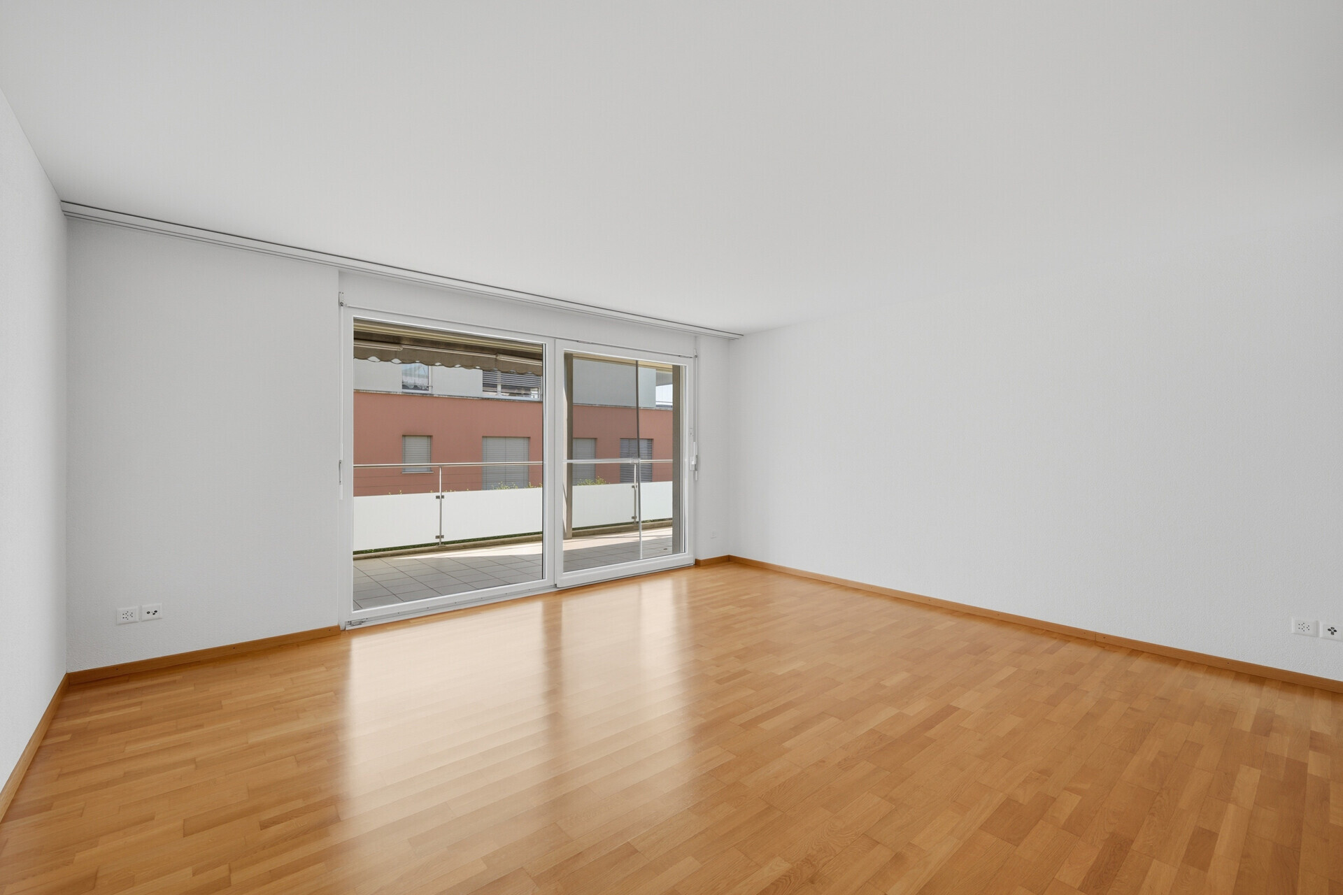 Leerer Wohnraum mit Balkonzugang