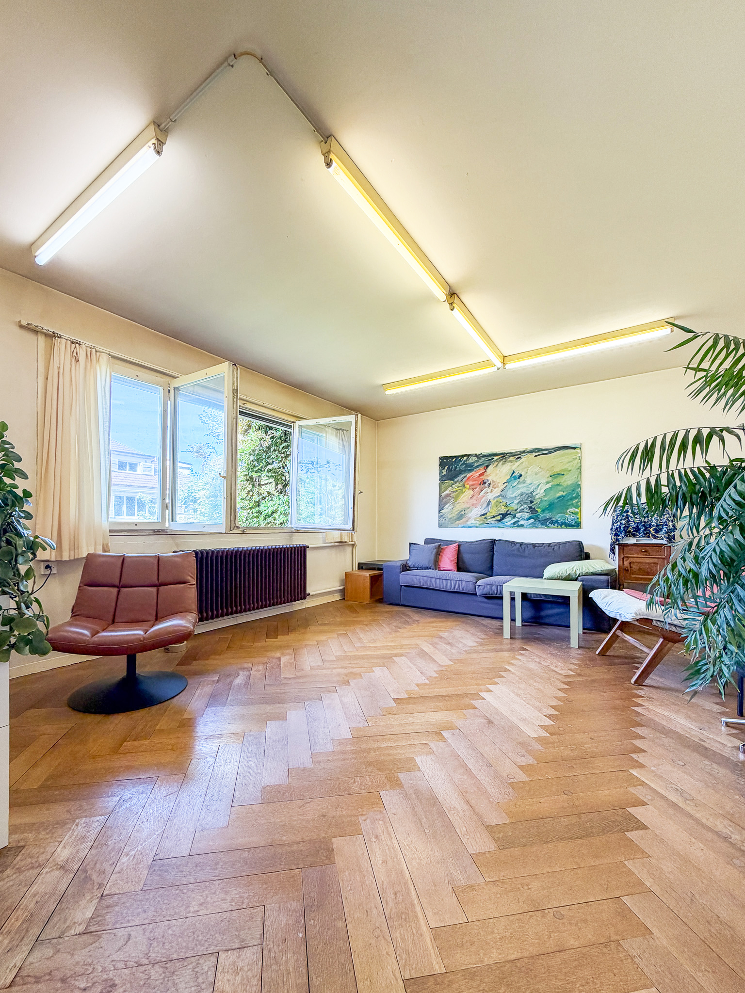 Helles Wohnzimmer mit Parkett und großen Fenstern
