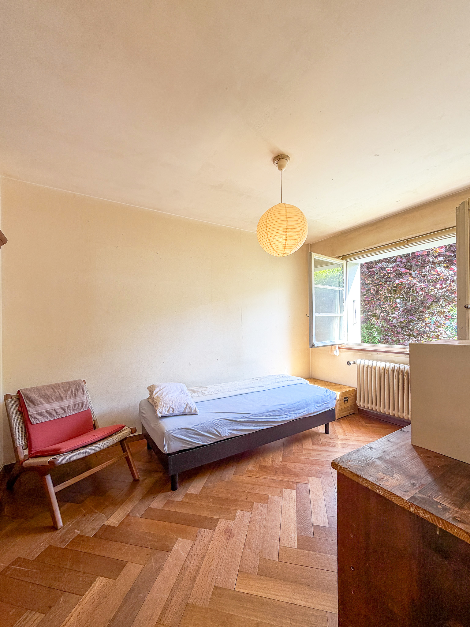 Helles Schlafzimmer mit Holzboden und offenem Fenster