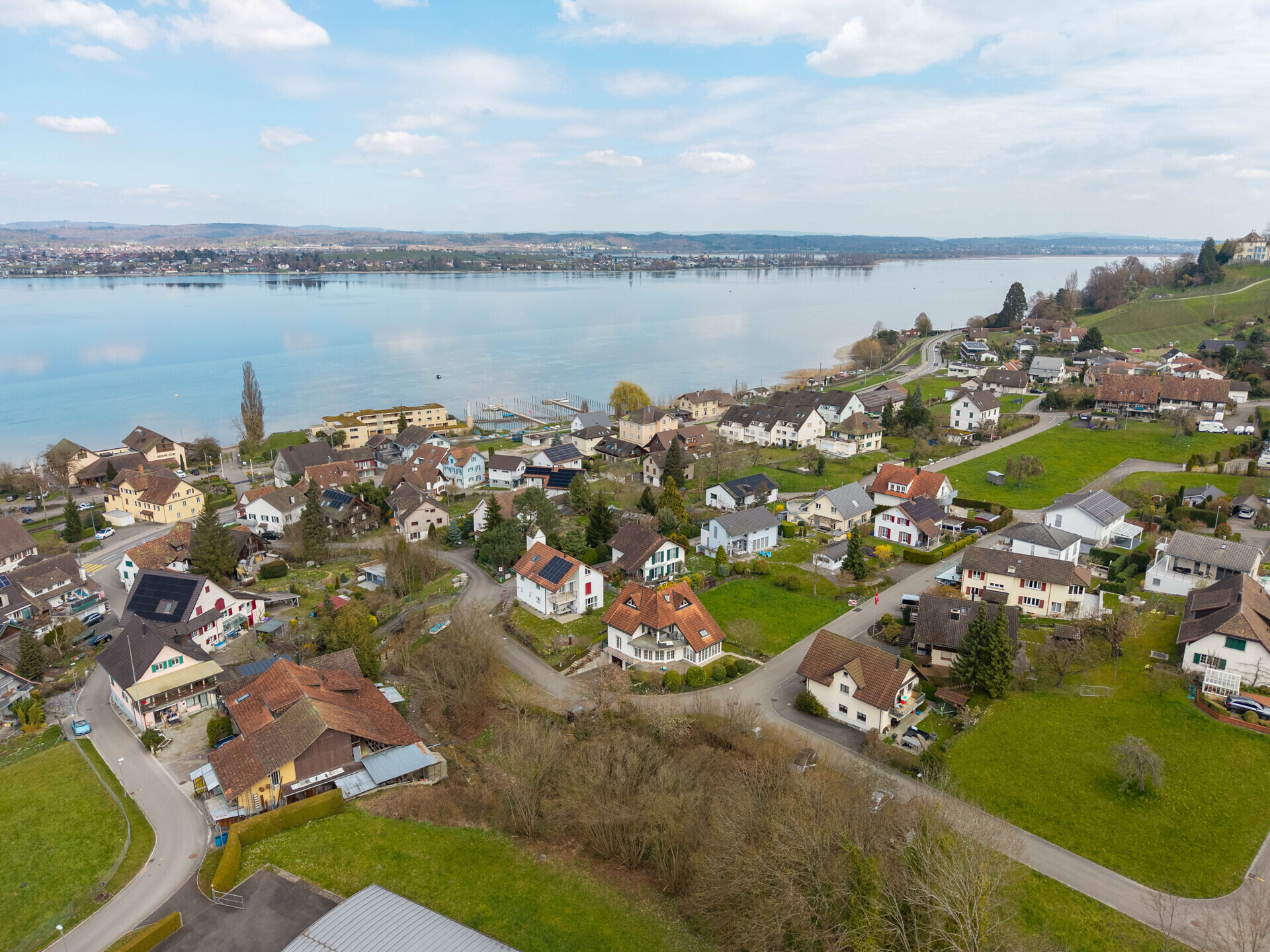 Luftaufnahme eines Seeufer-Orts mit Wohnhäusern