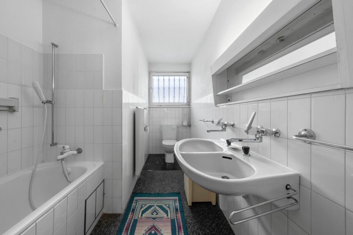 Schmales Badezimmer mit Badewanne, Waschtisch und WC