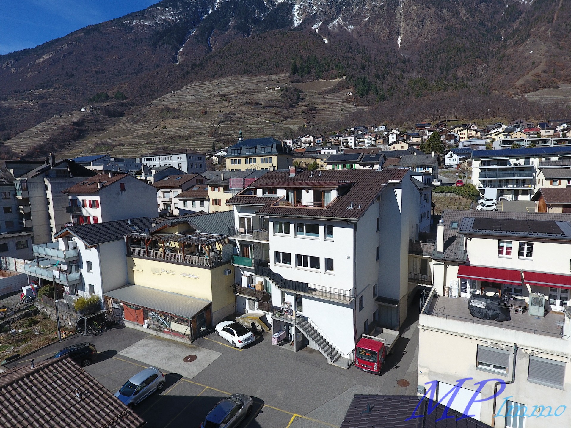 Drohnenaufnahme eines Wohnviertels in alpiner Landschaft