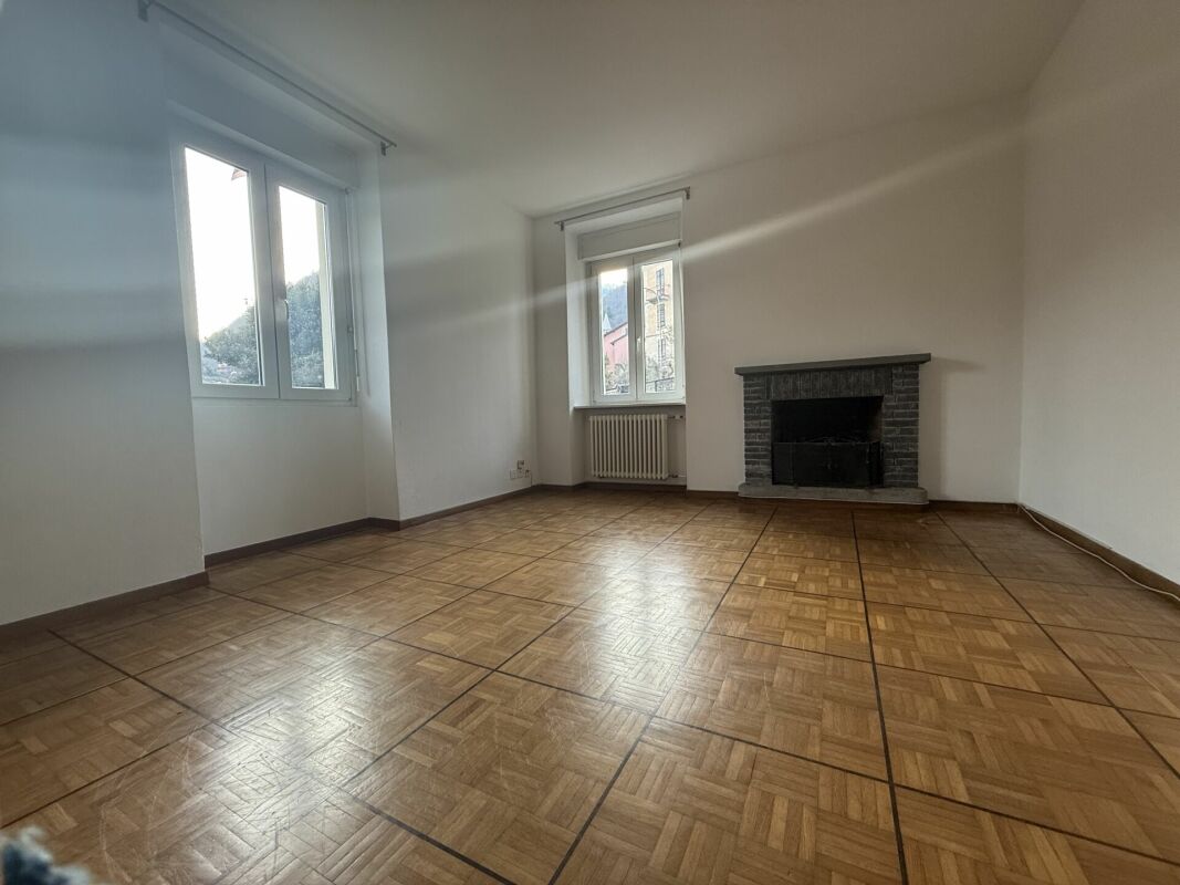 Leerer Wohnraum mit Kamin und Parkettboden