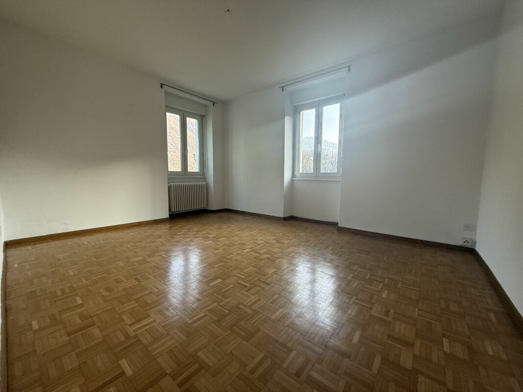 Leerer Wohnraum mit Parkett und zwei Fenstern