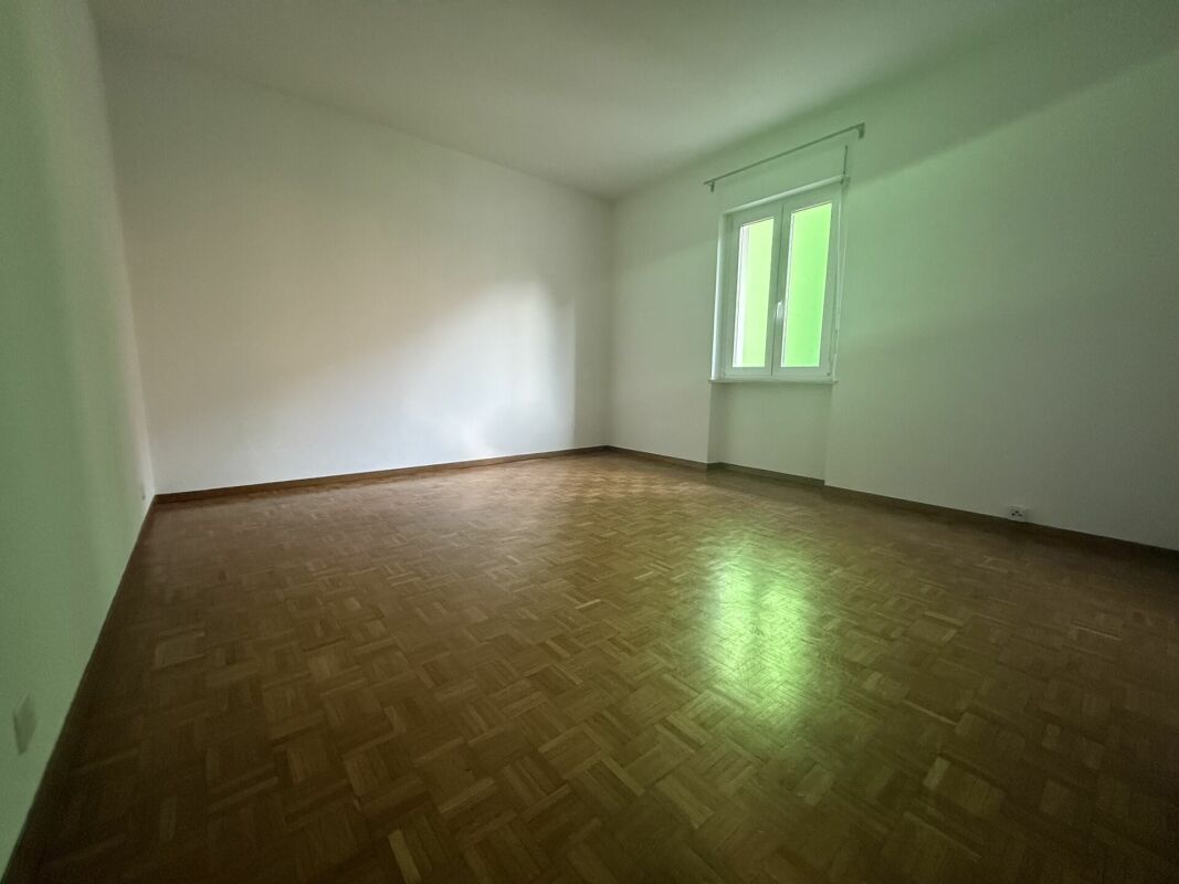 Leerer Wohnraum mit Parkettboden und Fenster