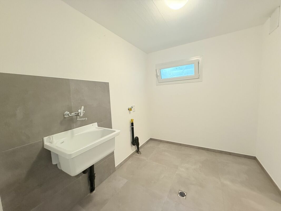 Heller Hauswirtschafts- oder Technikraum mit Waschbecken