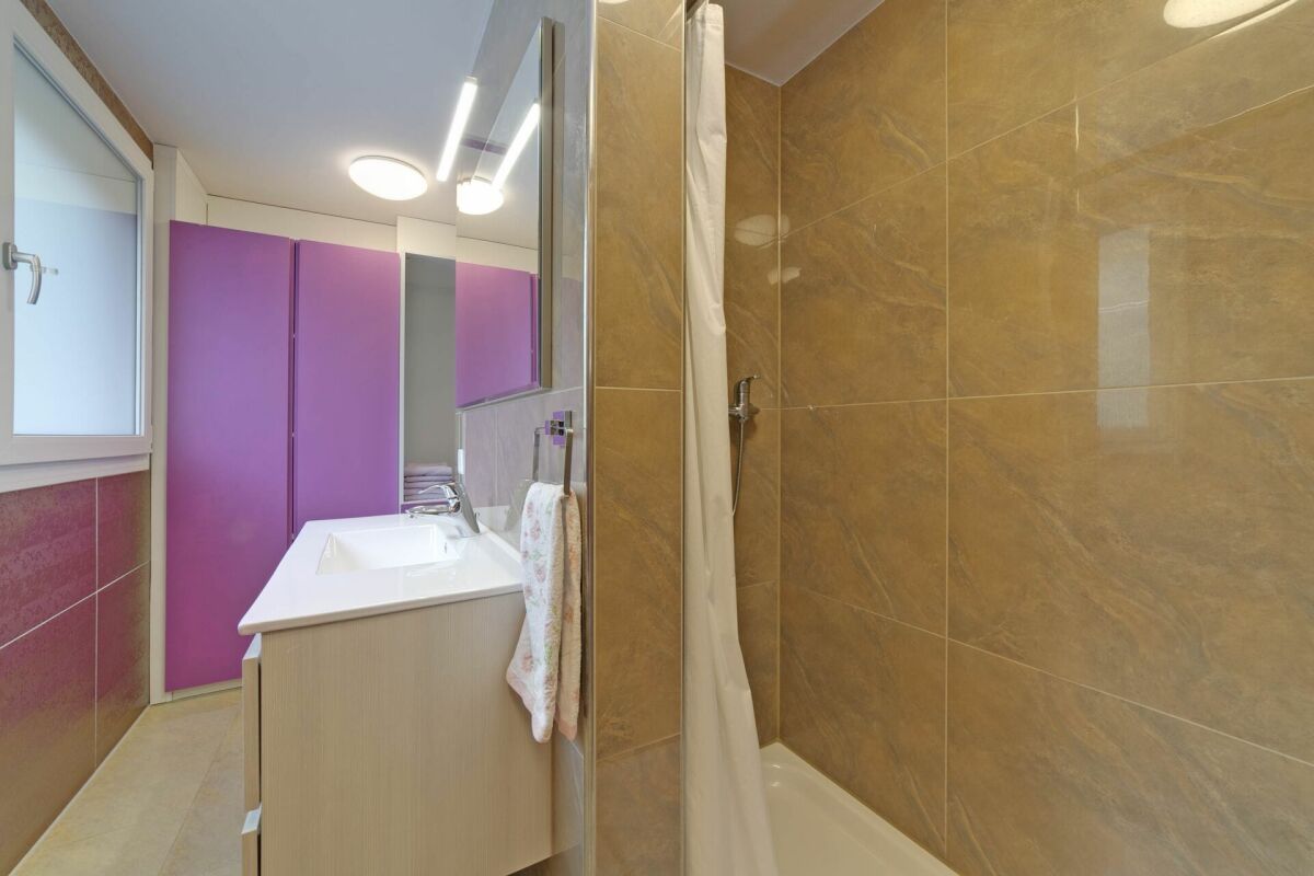 Modernes Badezimmer mit violettem Stauraum und beiger Dusche