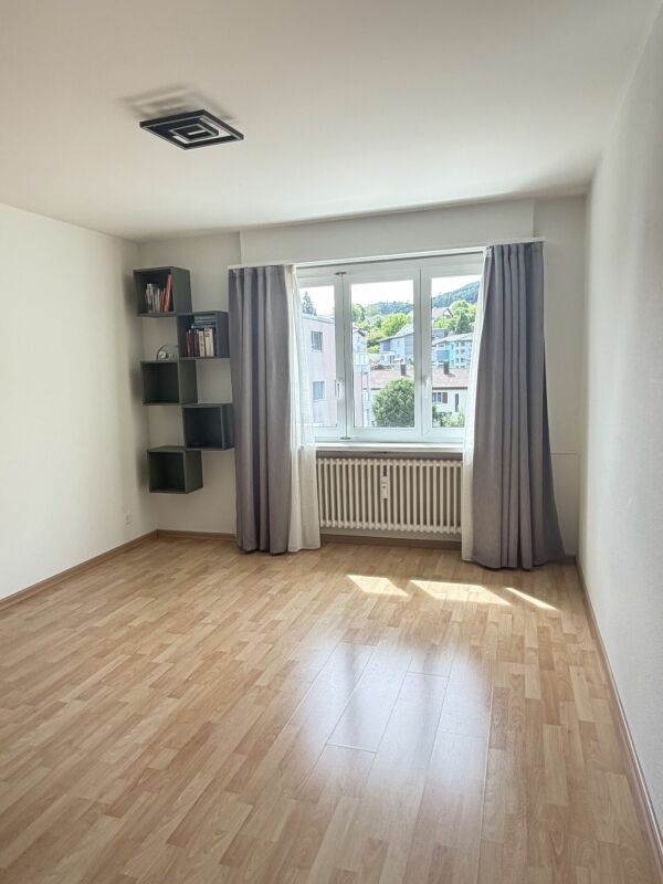 Leeres, helles Zimmer mit Fenster und Heizkörper