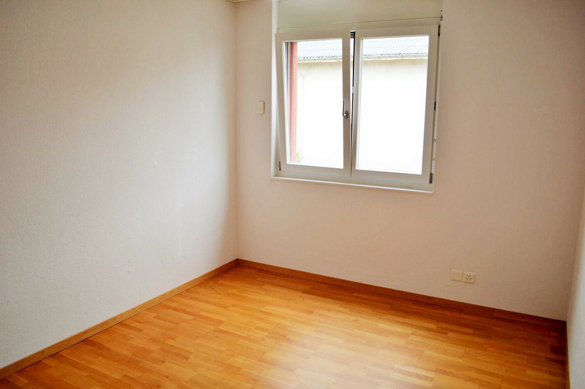 Leerer heller Raum mit Fenster und Holzparkett