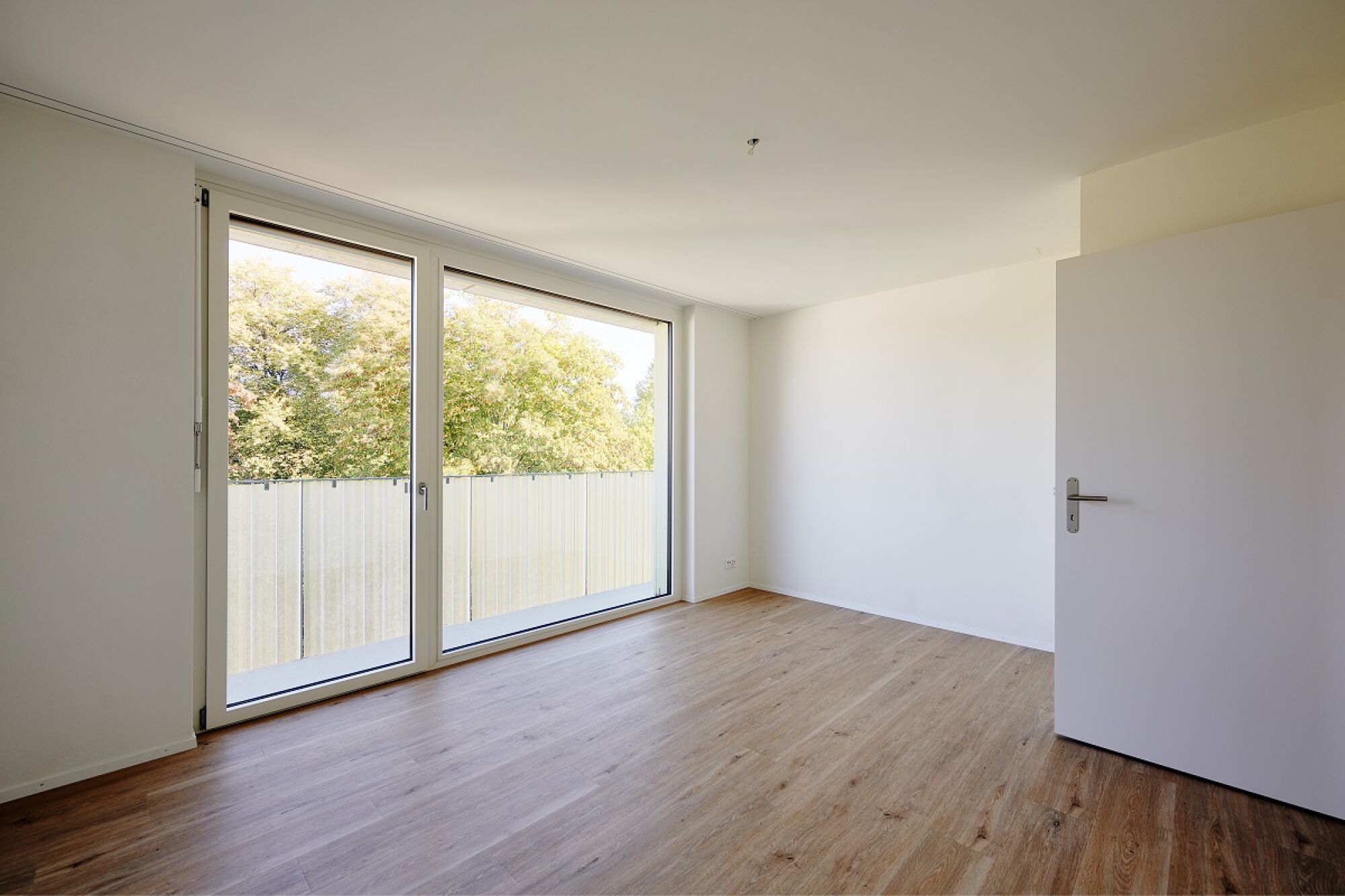 Leeres, helles Zimmer mit großer Fensterfront