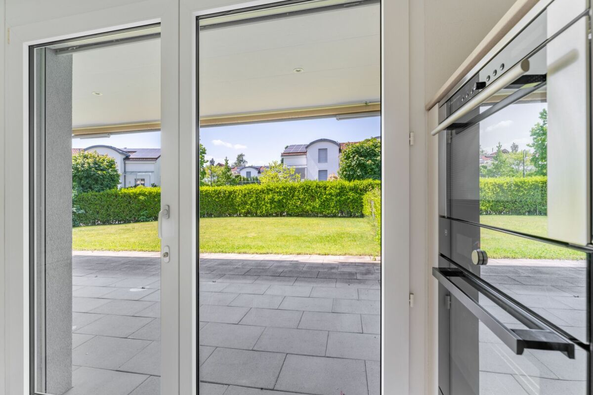 Blick durch eine helle Glasfront in den Garten
